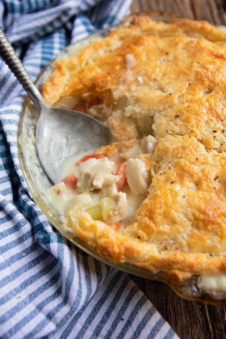a pie plate of chicken pot pie with a scoop out and a spoon in it