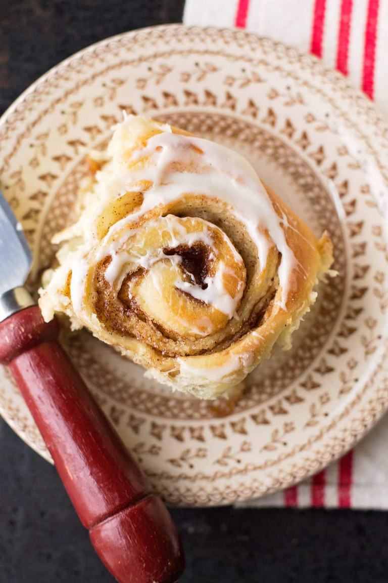 one cinnamon roll on a plate on a red napkin