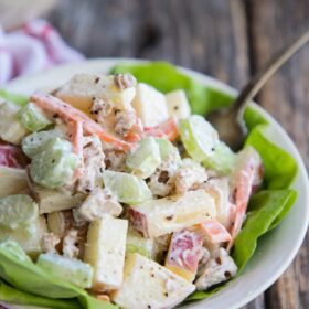 A bowl of Waldorf salad in a bowl with a fork and lettuce
