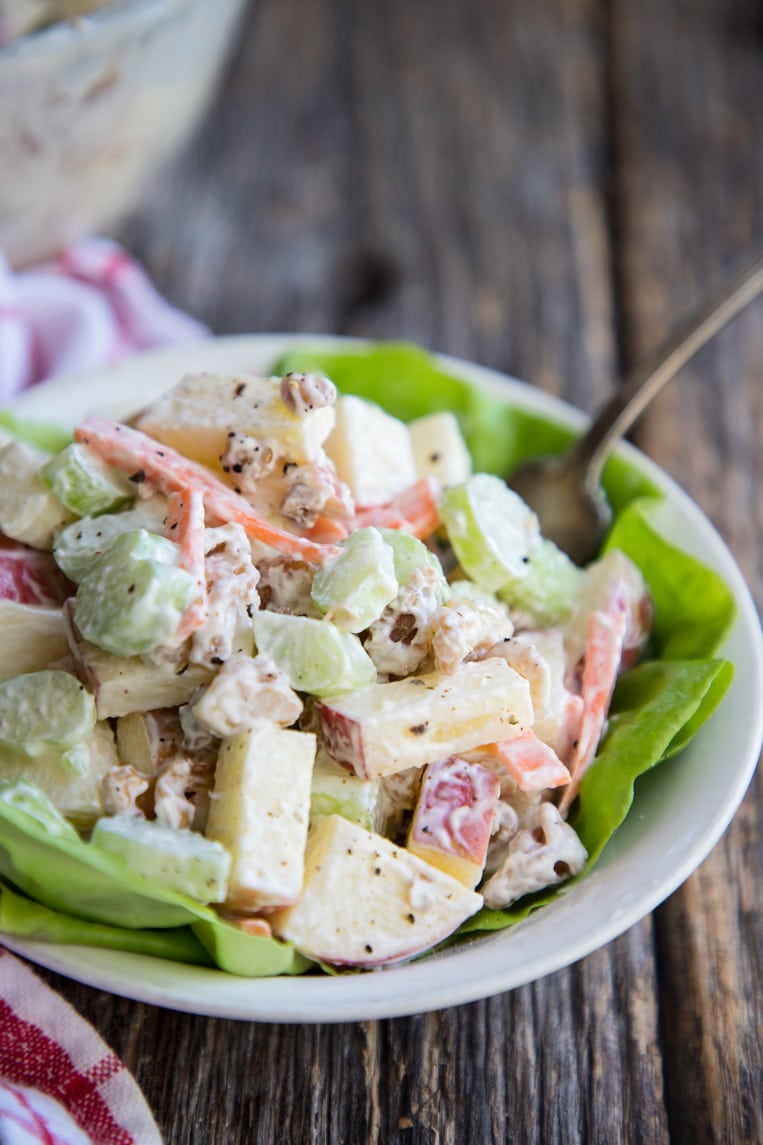 A bowl of Waldorf salad in a bowl with a fork and lettuce 