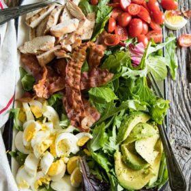 platter cobb salad with avocado, tomatoes, eggs and bacon and grilled chicken