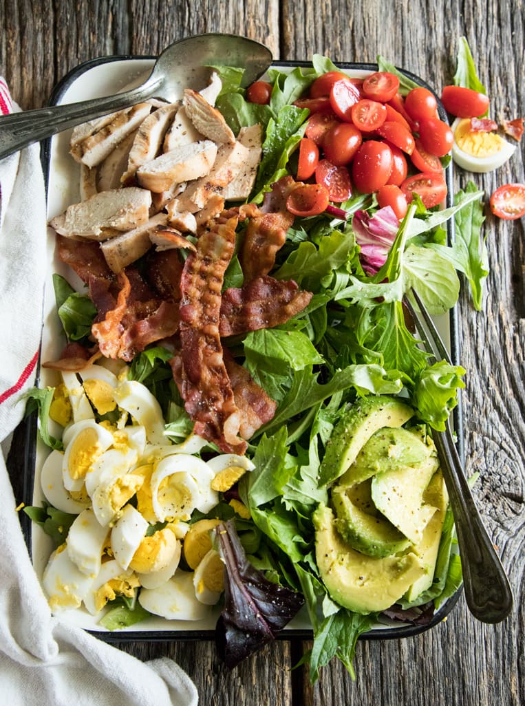 platter cobb salad with avocado, tomatoes, eggs and bacon and grilled chicken