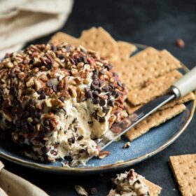 a chocolate chip dessert cheese ball on a plate with a knife and graham crackers