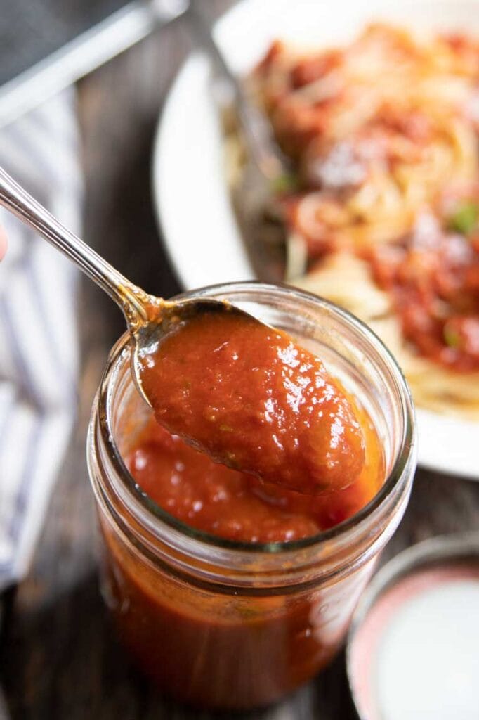 a jar of pasta sauce with a spoon lifting some out