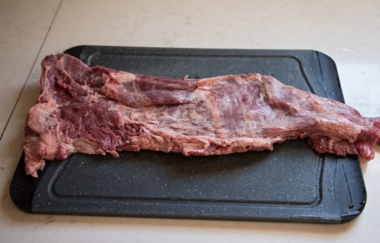 a skirt or flank steak unfolded on a cutting board for trimming