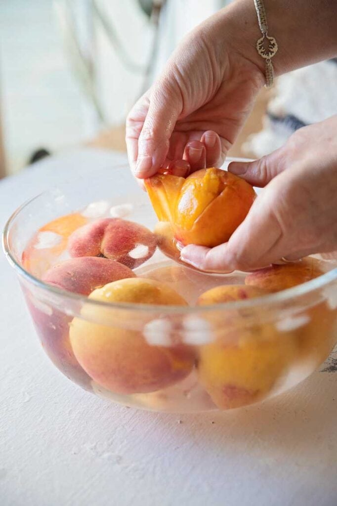 holding a peach and peeling away the skin from the top 