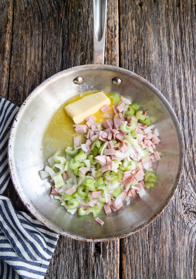 a skillet with melted butter, ham, celery and onions 