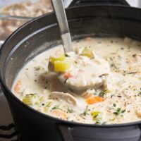 a ladle of leftover turkey soup being lifted from a dutch oven