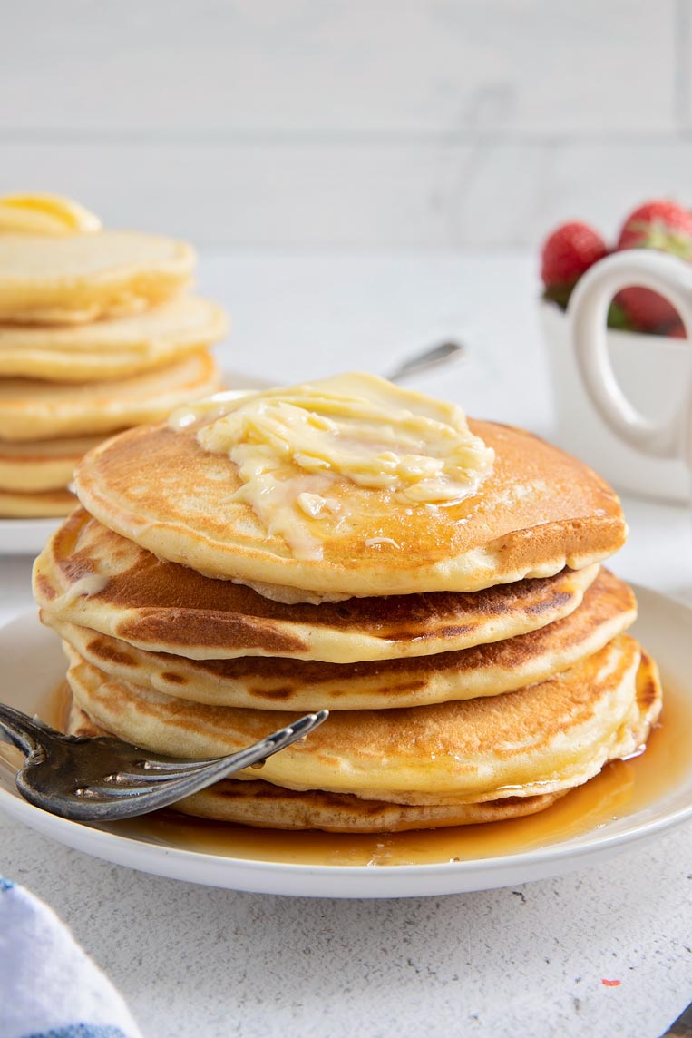 a stack of whole pancakes with syrup and butter on a plate