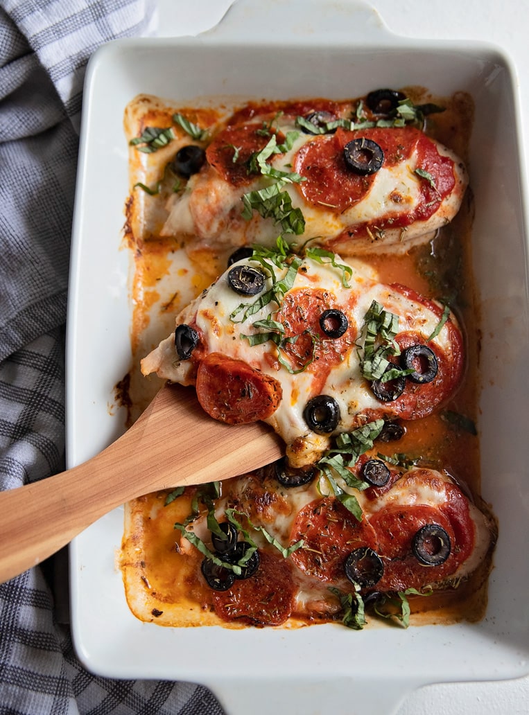 pizza baked chicken breasts in a baking dish with a spatula