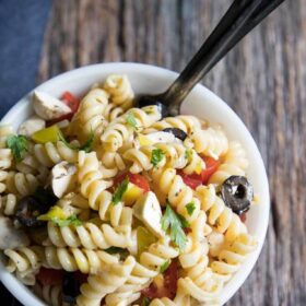 rotini pasta salad with mozzarella and tomato in a bowl with a spoon
