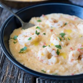 a bowl of shrimp and grits with a fork