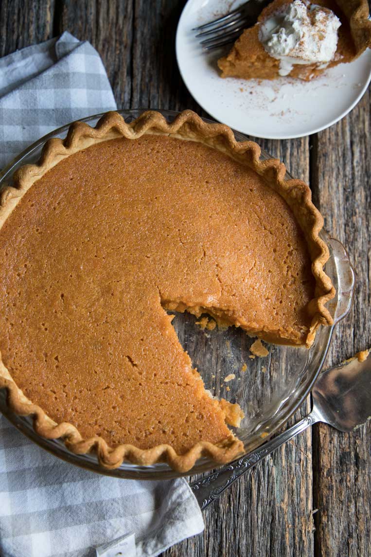 a whole southern sweet potato pie in a pie plate with a slice out. 