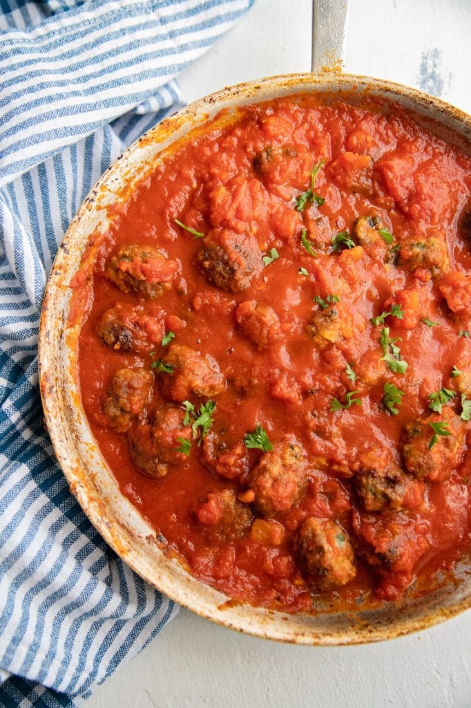 a big skillet of meatballs simmering in sauce