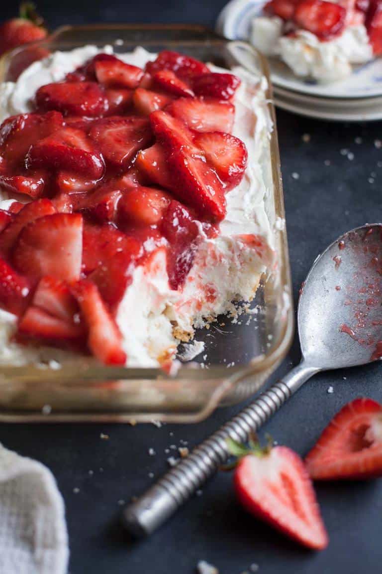 strawberry layered lush in a glass baking dish with a large spoon