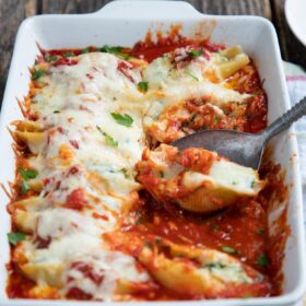 9x13 pan of stuffed shells with spinach on a wooden table.