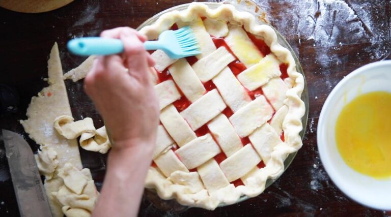 a lattice crust being brushed with egg wash before baking 
