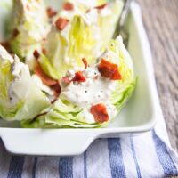 white dish of lettuce wedges with dressing and bacon