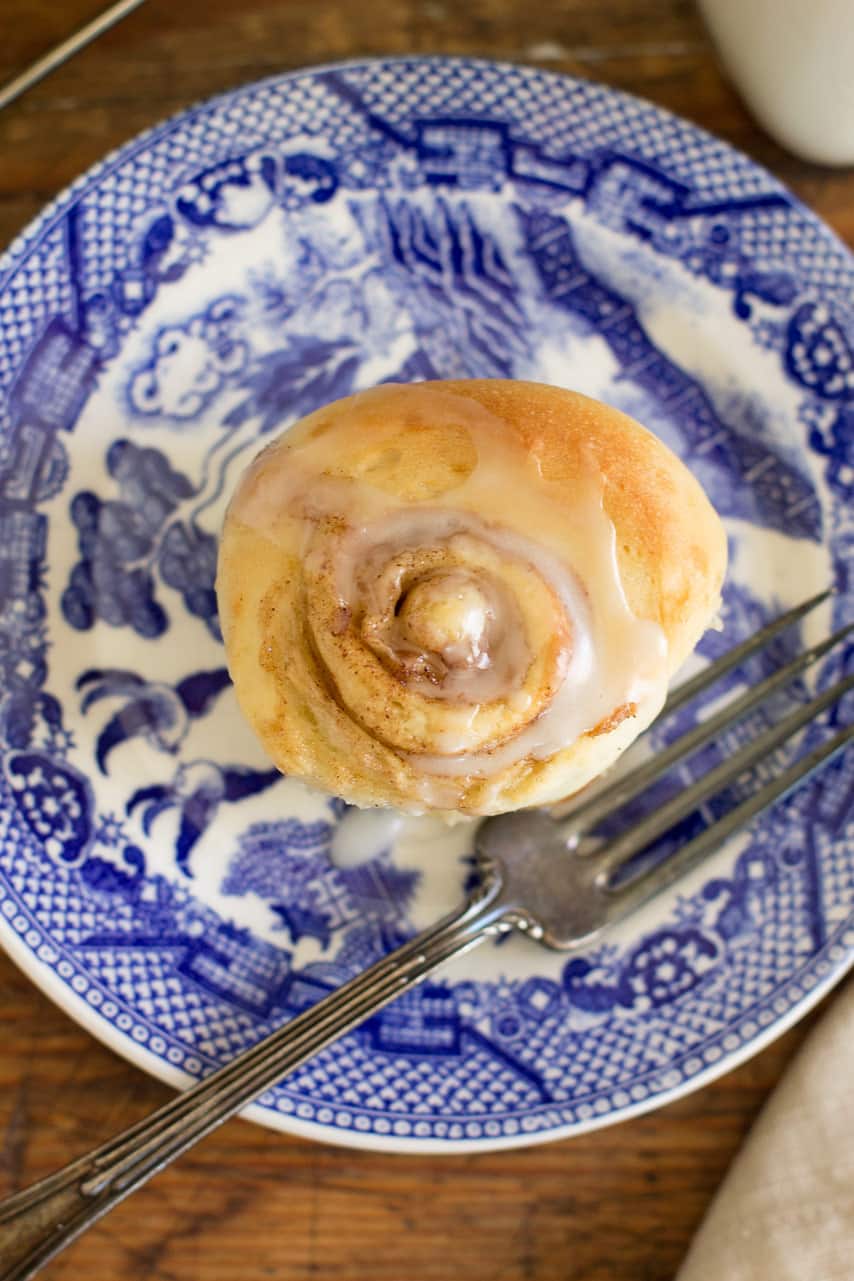 one cinnamon roll on a blue plate with a fork