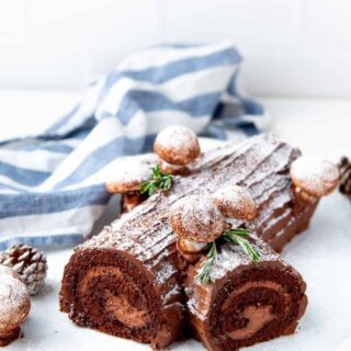 a baked chocolate yule log on a table with powdered sugar